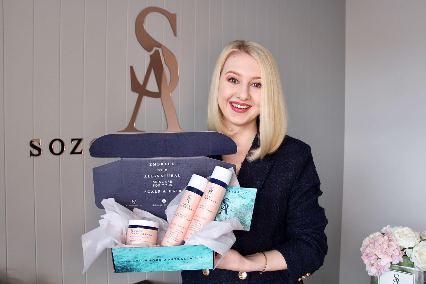 Sozo Australia's founder holding all-natural haircare bundle set containing Australian made shampoo, conditioner and hair mask